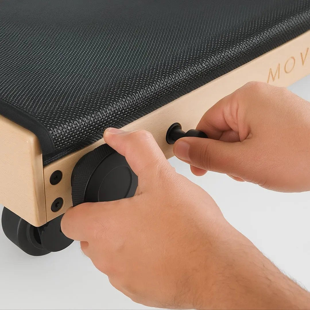 Close-up of hands adjusting the MOVELIO Bed Roller pressure settings for light or deep massage.