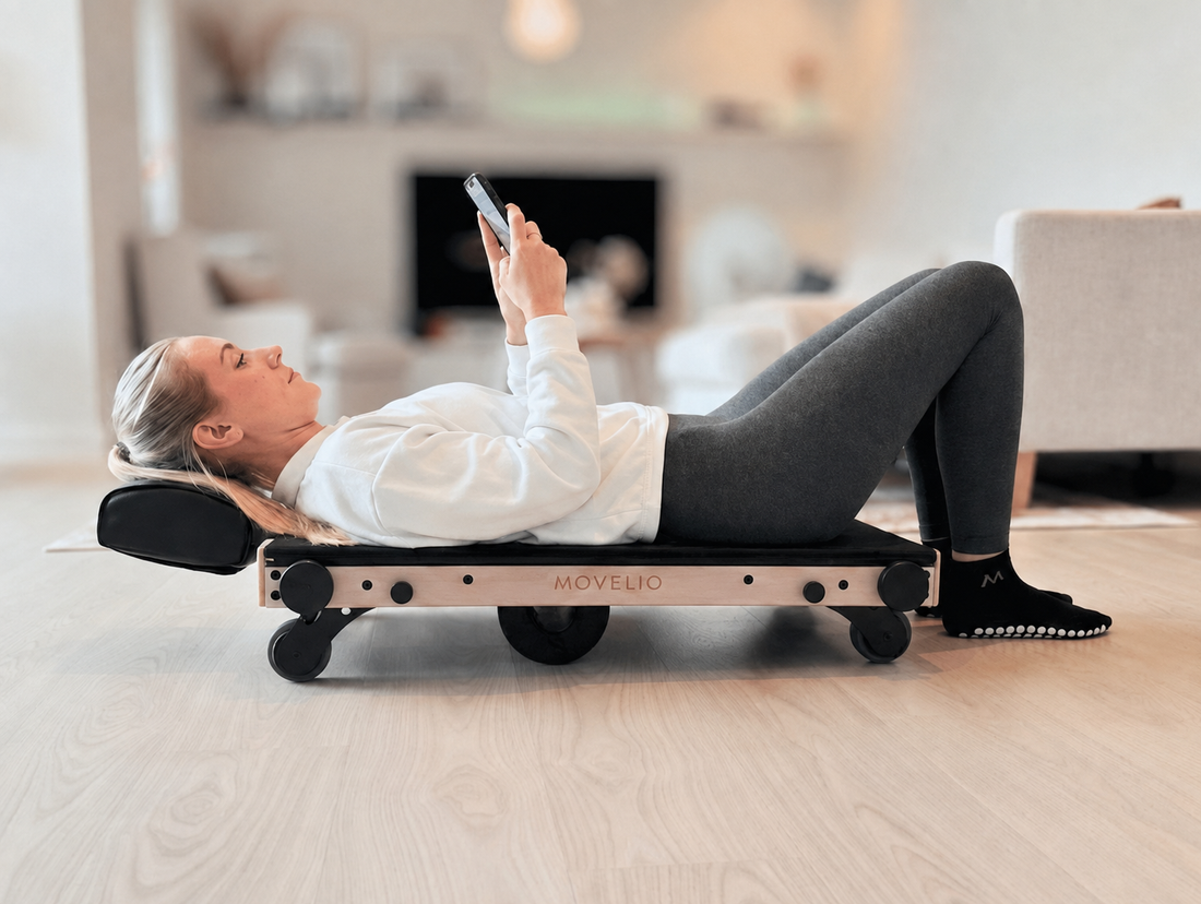 Woman using Movelio Bed Roller while viewing the Movelio Companion App