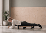 Woman using the MOVELIO Bed Roller on the front of her hips and thighs while lying face down.