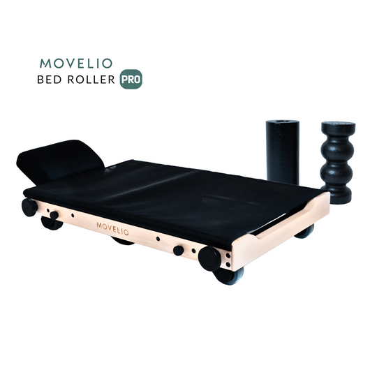 Movelio Bed Roller, a device for full-body massage, consisting of a flat base with wheels, a black cushion, and two black cylindrical rollers.