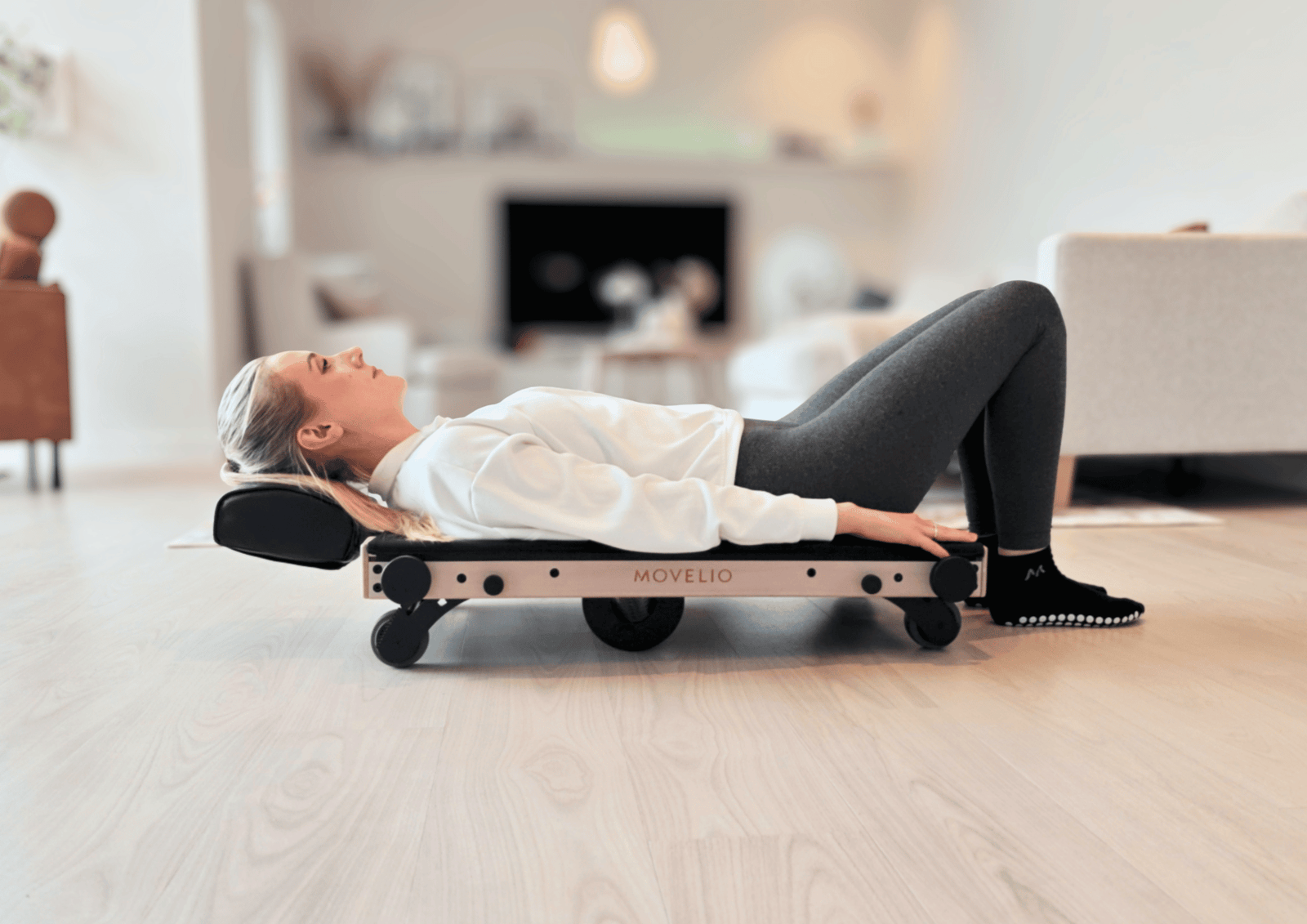 Woman using Movelio Bed Roller for back massage at home