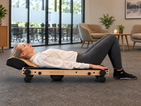 Woman using Movelio Bed Roller in a bright workplace, with the projecting contoured headrest and entire product visible.