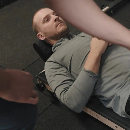 Man using the MOVELIO Bed Roller during a physiotherapy session with guidance from a therapist.
