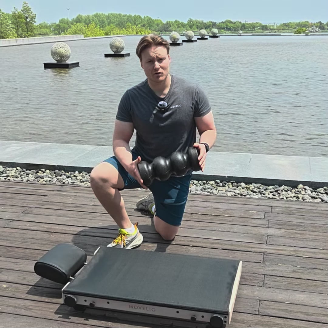 Last inn video: Personlig trener demonstrerer Movelio Bed Roller og forklarer funksjonene og bruken i detalj. Opptaket er gjort utendørs på en treterrasse.